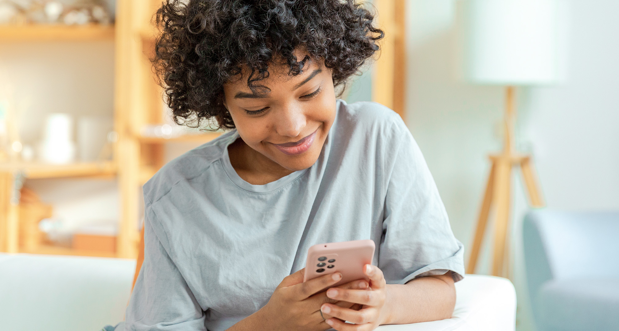 zdjęcie zbliżeniowe uśmiechniętej osoby patrzącej na telefon komórkowy