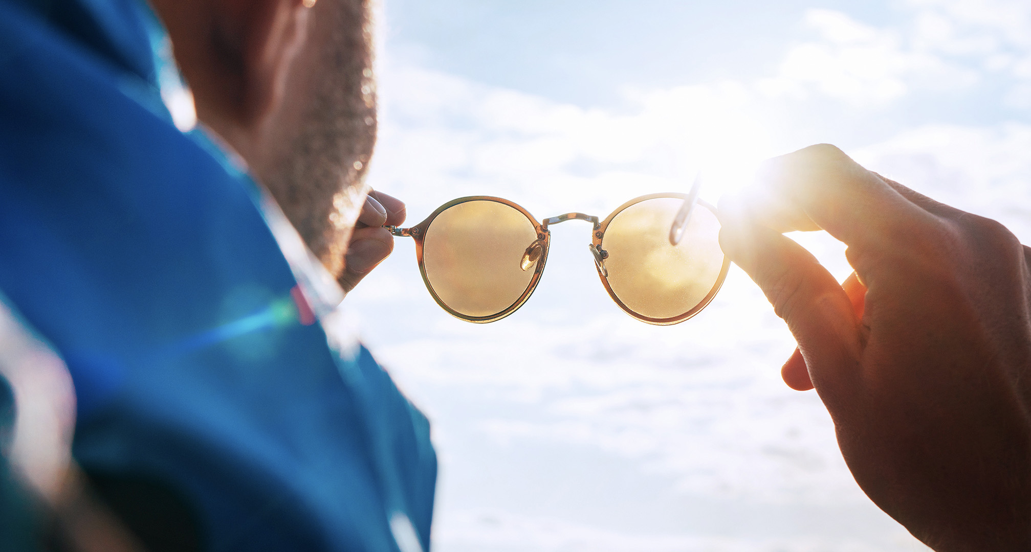 trzyma okulary przeciwsłoneczne pod słońce